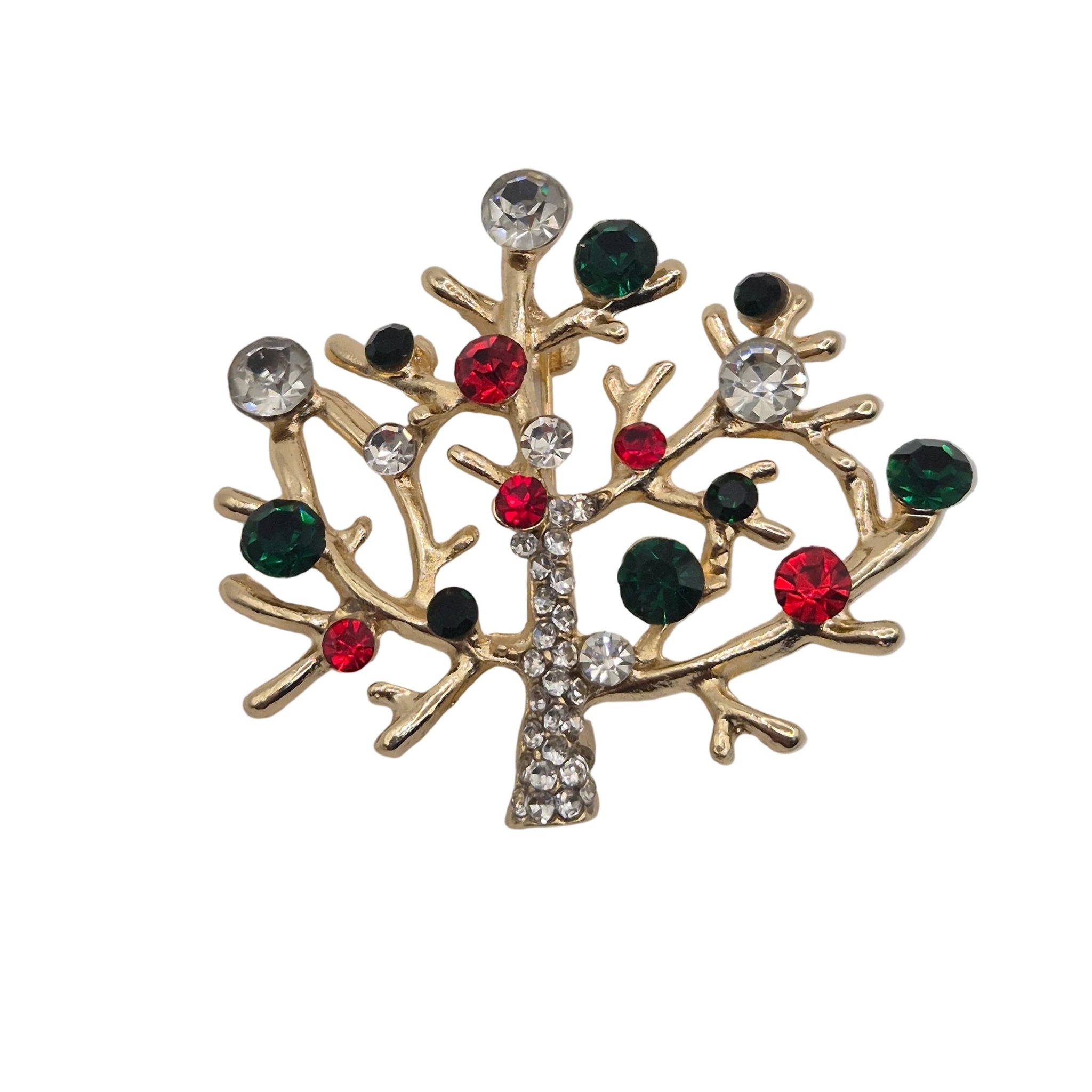 A gold-toned tree-shaped brooch decorated with faceted rhinestones in red, dark green and clear, set against a plain white background.