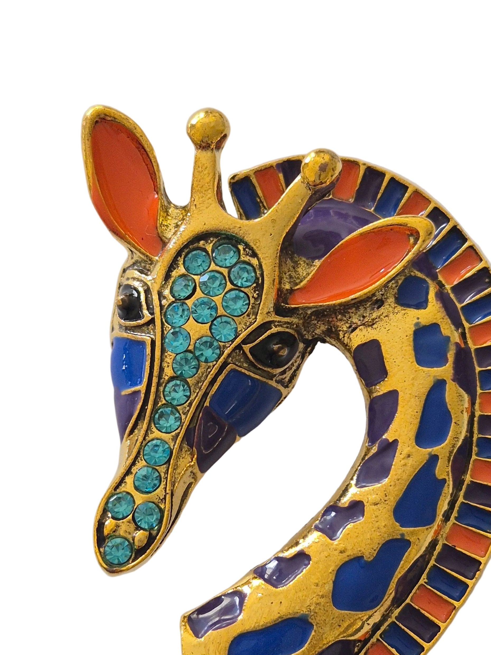 Colorful giraffe-shaped brooch with gemstone details on a white background