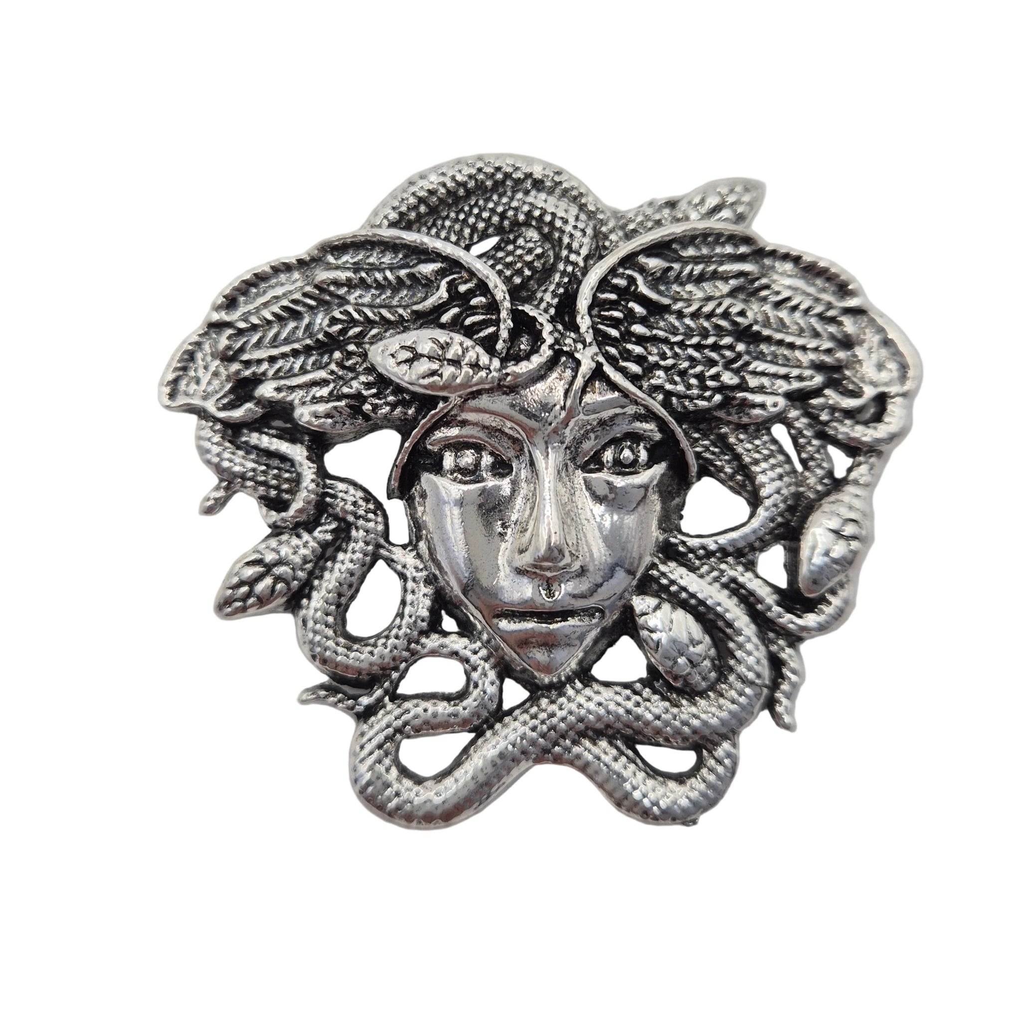 A silver-tone metal brooch featuring a Medusa head with snakes winding through leafy hair, shown on a plain white background.