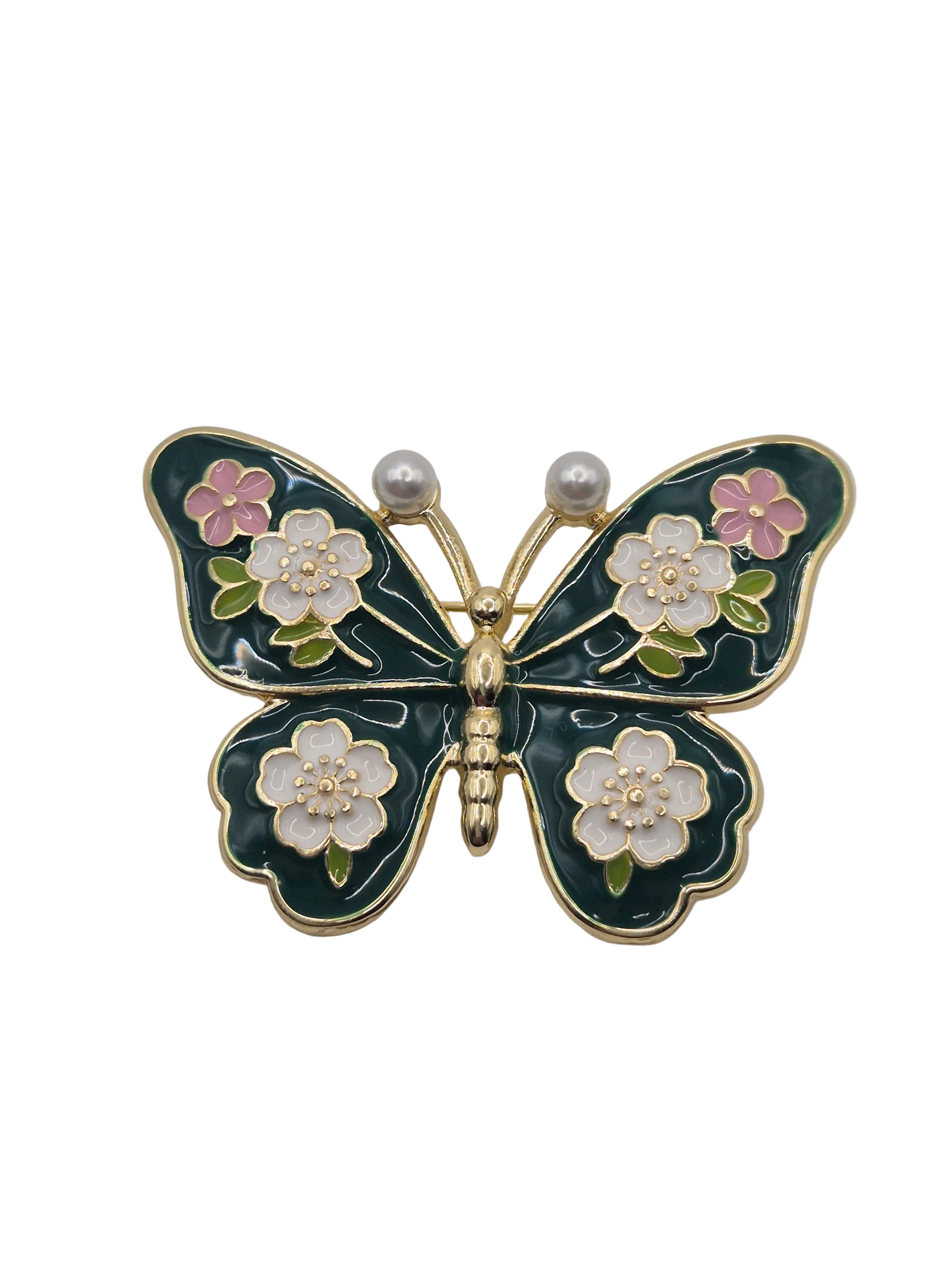 Butterfly-shaped brooch with floral details on a white background
