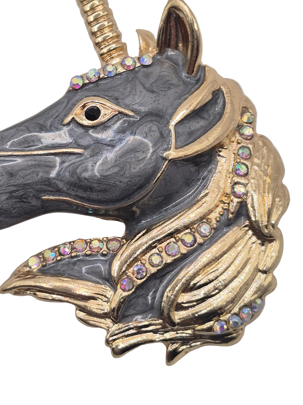 Unicorn head brooch with gold and black design on a white background