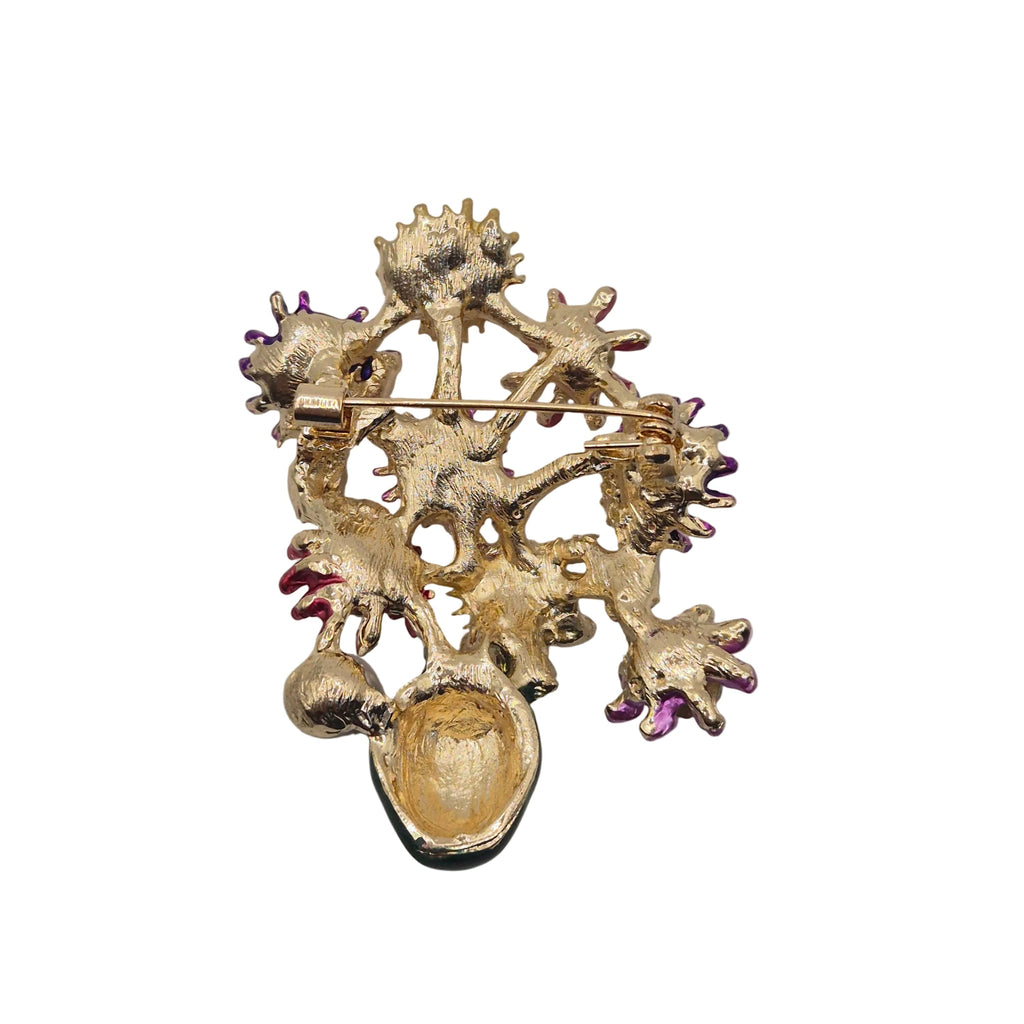 A gold-toned floral brooch  a gold pin clasp, shown on a plain light gray background.