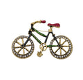 A bicycle-shaped brooch featuring gold-tone metal with green, black, red, and clear rhinestone details, set against a plain white background.
